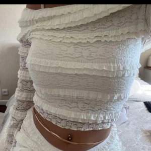 Offshoulder spetsblus med volang - Superfin offshoulder topp i vit spets med volanger över hela. Långa ärmar med utsvängda ärmslut och croppad passform. Aldrig använd men prislapp finns ej kvar. nypris 399. Passar storlek 36/38, sitter som storlek S