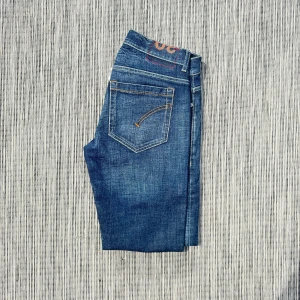 Dondup jeans - Säljer ett par blå jeansbyxor i klassisk modell med snygga kontrastsömmar och femficksdesign. Jeansen har en rak siluett och är tillverkade i slitstarkt denimtyg. Perfekta för dig som gillar en tidlös look.!AI BESKRVINING! Om ni vill ha fler bilder eller om ni har andra funderingar och frågor skriv.