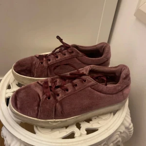 Vinröda sneakers i sammet, strl 37 - Snygga vinröda sneakers i sammet med matchande vinröda snören och vit platt sula. Skorna har rund tå och klassisk sneakerform, perfekta för dig som vill ha en unik touch på vardagslooken.