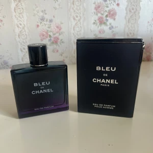 Bleu de Chanel Eau de Parfum 100ml - Bleu de Chanel Eau de Parfum för herr, 100 ml. Flaskan är stilren och fyrkantig i mörkblått glas med svart kork och silverdetaljer. Kommer med originalkartong i matchande mörkblå färg och tydlig Chanel-logga på korken och kartongen.