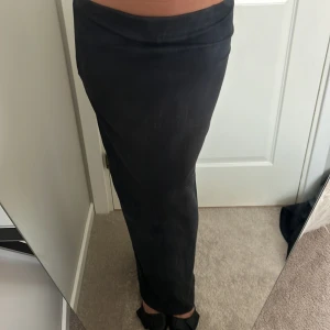 Svart långkjol från ONLY - Svart ribbad långkjol från ONLY med tight passform. Kjolen är enkel och stilren, perfekt att styla med sneakers eller boots. Materialet är stretchigt och följsamt, vilket gör den bekväm att bära hela dagen.