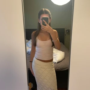 Vit stickad långkjol med mönster - Supersnygg  beige stickad långkjol med diskret hålmönster i rutor. Perfekt till sommarens alla outfits och ger en fräsch och trendig look.
