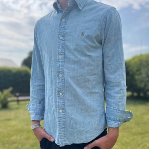 Ralph lauren slim fit skjorta 👔  - ☀️ Ralph Lauren blå skjorta – din sommardröm är här! 🧵 Slim fit med luftig känsla – 100% bomull som känns som linne. 👕 Perfekt för varma dagar och stilrena kvällar. 📏 Modellen är 176 cm och skjortan sitter som en smäck! 🌀 Klassisk look, modern känsla – klicka hem den direkt! 🙌