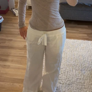 Vita linnebyxor från Alobha, S - Säljer ett par vita linnebyxor från Alobha i storlek S. Byxorna har bred resår i midjan, snörning framtill och raka, loose ben. Byxorna är uppsydda så att dem passar mig som är 164cm. Men dem är väldigt lätt att lägga ner igen!💕