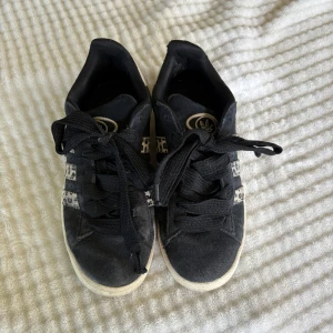 Adidas campus 00 sneakers med leopardmönster - Svarta Adidas sneakers med klassiska tre ränder i beige och leopardmönster. Skorna har svart snörning, rund tå och vit sula. Adidas-logga på plösen och hälen. Ovandelen är i mocka för en snygg och trendig look. Finns defekter och syns att dom är använda! Är i det skick som syns på bilderna!