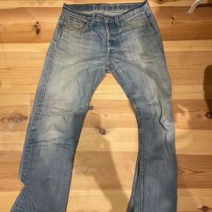 Levi's 501 ljusblå jeans straight fit - Klassiska Levi's 501 jeans i ljusblå tvätt med raka ben och femficksmodell. Jeansen har knappgylf, ikonisk läderpatch bak och den röda Levi's-taggen på bakfickan. Perfekta för en avslappnad och tidlös stil. W 31 L 34