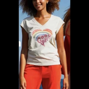Vit t-shirt med regnbåge från Coster - Vit t-shirt från Coster Copenhagen med färgglad regnbåge och texten 'Good Vibes' på bröstet. T-shirten har v-ringning och korta ärmar, tillverkad i mjuk bomull. Perfekt för dig som gillar en chill och färgglad stil.
