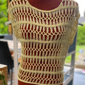 Gul virkad topp från KappAhl 36/38 - Virkat linne i en ljusgul nyans med ett öppet, luftigt mönster. Perfekt för varma dagar eller som ett lager över en annan topp.  Längd: 55 cm, bystvidd: 55 cm  Inga bilder när den sitter på mig! Katter finns i hemmet!