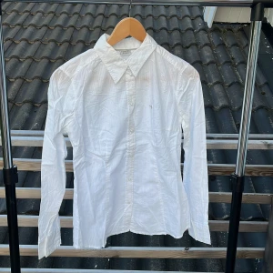 Vit skjorta från Esprit, strl 38 - Klassisk vit skjorta från Esprit i storlek 38. Skjortan har diskreta ränder i tyget, lång ärm och knäppning framtill. Perfekt krage och enkel, stilren look som funkar till många outfits.