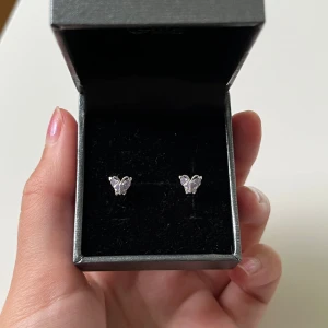 Söta fjärilsörhängen i silver  - Ett par små örhängen i form av fjärilar i äkta silver med  lila stenar som vingar. I helt nytt skick,  Perfekta för dig som gillar gulliga detaljer.