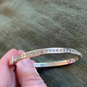  Armband/armring från Snö of Sweden - Säljer ett stilrent armband i silverfärg med en rad gnistrande stenar längs ovansidan. Armbandet är stelt och har ett diskret spänne. Perfekt för dig som gillar lite extra bling i vardagen. Är ej använt endast testat. Vikt 15 gram, se bild 5 för storlek. Nyskick! 
