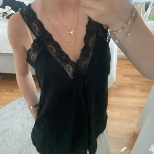 Svart linnetopp med spetsdetaljer - Supersnygg svart linnetopp med breda spetskanter längs v-ringningen och axelbanden. Perfekt sval topp för varmare dagar☺️☺️