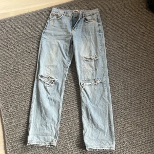 Ljusblå jeans med hål, stl 38  - Ett par ljusblåa jeans med hål i, köpta från Gina tricot, stl 38. Har använt dom en del så de kan vara något slitna men inget som syns direkt. 