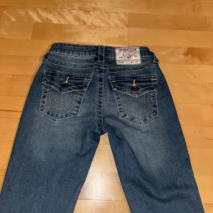 Blå jeans från True Religion - Snygga bootcut, blå jeans från True Religion med klassisk femficksdesign och kontrasterande sömmar. Knappt använda och därför nyskick och även därav priset. Jag säljer dem då jag har bytt stil och då inte har någon användning av dem💕🫶