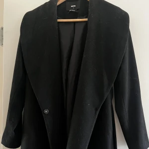 Svart kappa från Bik Bok - Snygg svart kappa från Bik Bok i storlek S med ett bälte i midjan, går ner till ungefär knävecken på mig (165cm lång). Använd fåtal gånger, mestadels hängt i garderoben. 