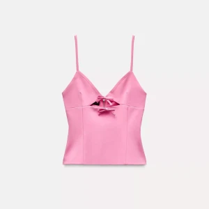 Zara topp - Söt rosa linnetopp med smala axelband och dekorativa rosetter framtill. Perfekt för en somrig look.