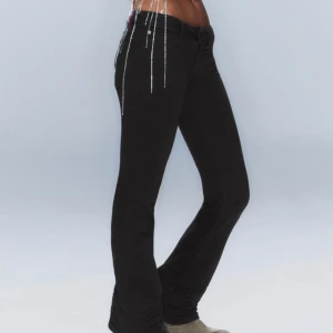 Svarta bootcut jeans - Snygga svarta bootcut jeans med låg midja och dragkedja. Perfekta för en stilren look. De har en klassisk design med knapp och dragkedja framtill. Innerben: 77