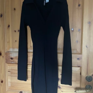 Svart långärmad klänning  - Snygg svart långärmad klänning med en v-ringad design. Perfekt för en stilren look. Klänningen har en figurnära passform och är tillverkad i ett ribbat material.