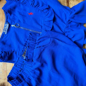 Blå set shorts och topp från Polo Ralph Lauren - Snygga blå shorts och topp från Polo Ralph Lauren med elastisk midja för extra komfort. De har en liten röd logga broderad på framsidan. Passar XS-S alternativt liten M
