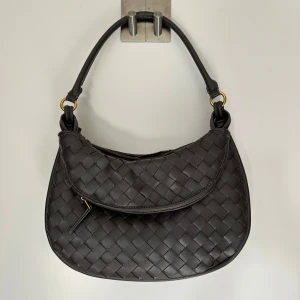 Bottega dupe - Snygg grå axelväska med flätat mönster och dragkedja. Väskan har en elegant design med guldfärgade detaljer och en bekväm axelrem. Det medföljer en längre rem, aldrig använd! Gjord av veganskt läder