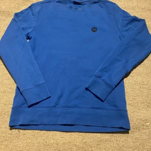 J Lindeberg tröja blå - Säljer en stilren blå J Lindeberg tröja med rund hals och långärmade. Perfekt för en Laidback eller Girish.