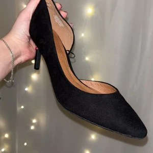 Svarta pumps från H&M - Eleganta svarta pumps i mocka från H&M med spetsig tå och klack. Perfekta för en stilren look.