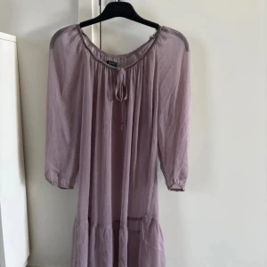 Ljuslila klänning från Esprit - Säljer en ljuslila klänning från Esprit med trekvartsärm och knytning vid halsen. Klänningen har en avslappnad passform och är perfekt för vår och sommar. Den mjuka färgen och enkla designen gör den lätt att matcha med olika accessoarer. Storlek M