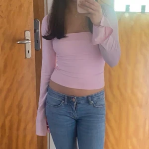 Rosa långärmad topp - Säljer en söt rosa långärmad topp med en stilren design. Toppen har en croppad passform och en elegant drapering framtill. Perfekt för att ge en feminin touch till din outfit. 💖