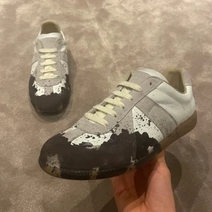 Maison Margiela Gats - Ett par Maison Margielas med paint splatter i skick 8/10. Mockan är lite skiten på vissa ställen och skorna kom utan skosnören så fick slänga på ett par gamla skosnören som är väldigt lika de Margielas annars har. Inget og tillkommer endast en Therealreal dustbag och skosnören på bild kommer också med. Vid frågor och funderingar är de bara att höra av sig👍 kan även tänka mig att gå ner i pris vid snabb affär!