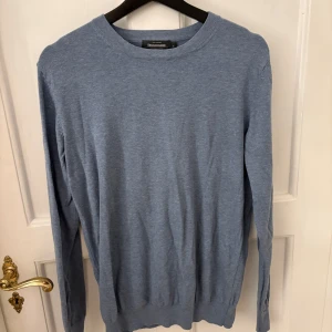 Blå tröja från dressmann - Snygg blå tröja från dressman i en klassisk design. Tröjan har långa ärmar och en rund halsringning, perfekt för en stilren look. Passar bra till både jeans och chinos🌟