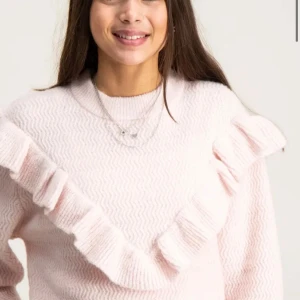 Ljusrosa stickad tröja med volang från young gina - Säljer en söt ljusrosa stickad tröja med volangdetaljer över bröstet. Tröjan har långa ärmar och en rund halsringning. Perfekt för en mysig och stilren look. Använt 1 gång, absolut inget fel på den! 