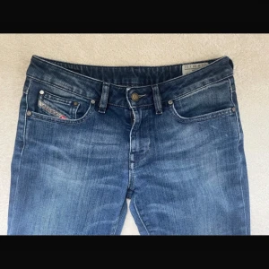 Blåa diesel jeans med slitningar - Snygga blå lowaist bootcut jeans från diesel med slitningar på låren och knäna. De har en klassisk femficksdesign och en knappgylf. Perfekta för en avslappnad stil. W30 L32. Pris kan diskuteras