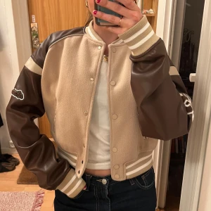 Beige och brun bomberjacka - Beige och brun baseballjacka från Manière De Voir med broderade detaljer på ärmarna. Faux läder. Använd endast ett fåtal gånger✨