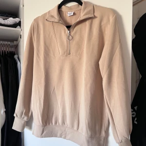 Beige tröja med dragkedja - Säljer en stilren beige tröja från Stories med dragkedja och ringdetalj vid halsen. Tröjan har långa ärmar och muddar vid ärmslut och nederkant. Perfekt för en avslappnad look. Önskar du veta exakta mått? Tveka inte att höra av dig!