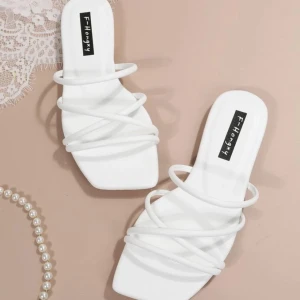 Vita sandaler med remmar - Stilrena vita sandaler med flera tunna remmar som korsar över foten. Perfekta för en somrig look med en fyrkantig tådesign. Lätta att matcha med olika outfits. Ingen klack.