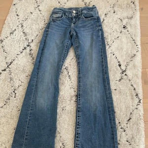 Blå jeansbyxor från Gina Tricot - Snygga blå jeansbyxor från Gina Tricot i storlek 146. Byxorna har en klassisk femficksdesign och stängs med dubbelknapp och dragkedja. Perfekta för en avslappnad stil med en bootcut passform. Justerbar resår i midjan💖 Använt ett fåtal ggr🥰
