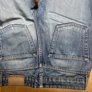 Blå jeans från DKNY - Snygga blå jeans från DKNY med klassisk femficksdesign och en lätt tvättad look. De har en normal passform och är perfekta för en avslappnad stil. Märkeslappen sitter på baksidan av midjan.