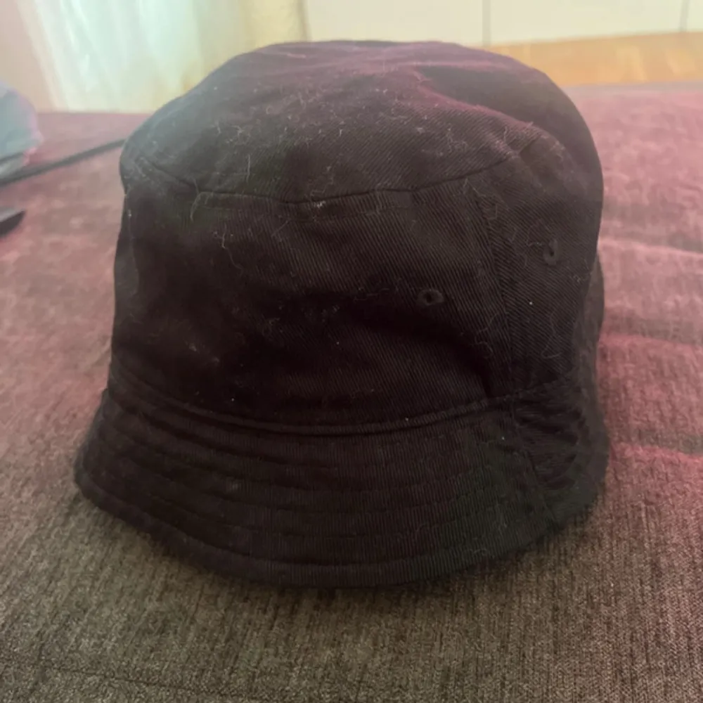 Snygg svart bucket hat från H&M. Perfekt för en avslappnad stil. Tillverkad i bomull för en bekväm passform. Enkelt att matcha med olika outfits.. Asusteet.
