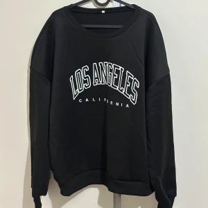 Svart sweatshirt med Los Angeles-tryck - Snygg svart sweatshirt med texten 'Los Angeles California' i vitt på framsidan. Använd 2-3 gånger dock Lite nopprig 