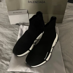 Svarta sneakers från Balenciaga - Snygga svarta sneakers från Balenciaga med en modern design. Skorna har en strumpliknande passform och en chunky vit sula som ger en cool kontrast. Perfekta för dig som vill ha både stil och komfort.