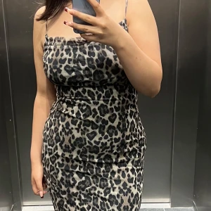 Leopardmönstrad långklänning - Snygg leopardmönstrad långklänning med smala axelband. Perfekt för en djärv och trendig look. Klänningen har en figurnära passform som framhäver silhuetten.