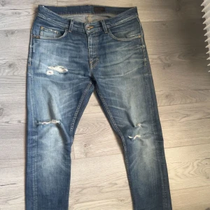 Blå jeans med slitningar - Snygga blå tiger of sweden jeans med slitningar på framsidan för en trendig look. De har en klassisk femficksdesign och en dragkedjgylf. Perfekta för en avslappnad stil. 32/34, nypris 1699kr