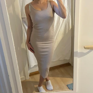 Beige ribbad klänning - Snygg beige ärmlös klänning med en tight passform från H&M. Strlk S. Säljer då den inte kommer till användning. 