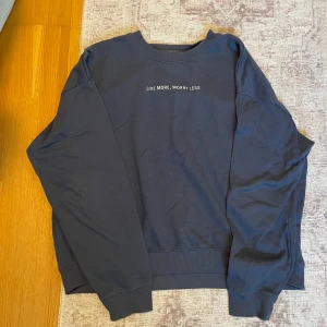 Mörkblå sweatshirt med text - Säljer en mörkblå sweatshirt med texten 'Live More, Worry Less' på bröstet. Tröjan har långa ärmar och ribbade muddar vid ärmslut och nederkant. Perfekt för en avslappnad stil.