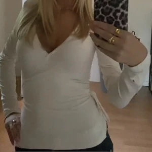 Vit omlottopp med knytband - Säljer en stilren vit omlottopp med långa ärmar och knytband i midjan. Perfekt för en elegant look. Passar bra till både jeans och kjol. Använd ett par gånger men tröjan är i god skick!!! ❤️