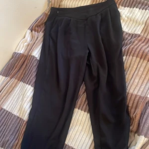 Svarta kostymbyxor - Snygga svarta kostymbyxor med en elegant och stilren design. Byxorna har en hög midja och en rak passform som ger en klassisk look. Perfekta för en chic och professionell stil.
