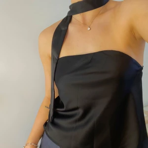 Svart tubtopp och scarf från Missguided - Supersnygg tubtopp och scarf i satin! Helt oanvänd med lappen kvar från Missguided 🦋Passar både på fest och till vardags! Är en del av ett set tillsammans med en maxikjol som jag säljer separat 🫶🏼