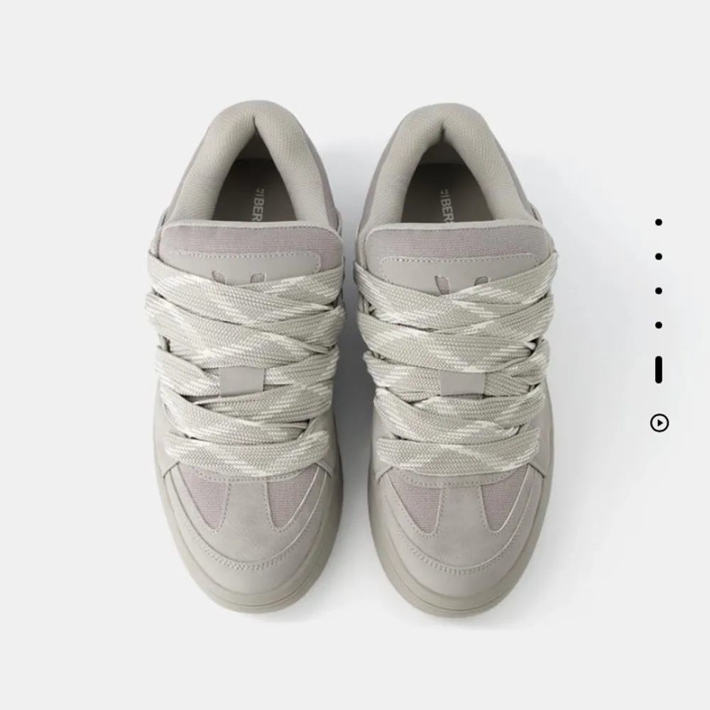 Snygga grå sneakers med breda snören och en stilren design. Skorna har en robust sula och är perfekta för en avslappnad stil. De är tillverkade i syntetmaterial och har en modern look. Skorna är från Bershka! Knappast använda. Skorna är för män.. Kengät.
