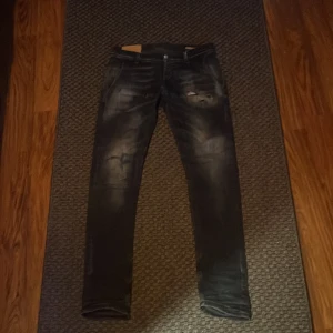 Svarta dondup jeans med slitningar - Snygga svarta dondup  jeans med slitningar och en cool tvättad look.