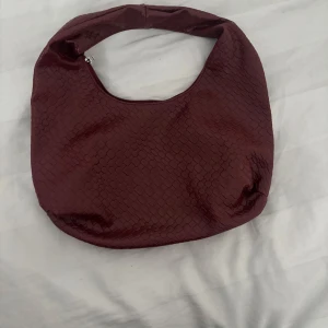 Röd väska - Vin röd väska, köpt på marknad i Italien. Säljs pga ej kommit till användning. Ny skick, utan prislapp. Pris kan kompromissas om. Perfekt fest väska eller om man ska gå på stan etc.